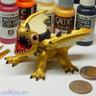 A small statue of a shiny gold dragon. The figurine is roaring, and has large cute eyes.