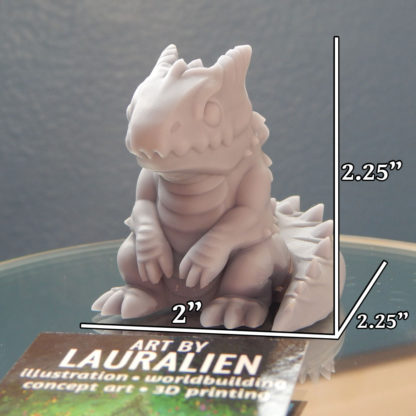 A small, unpainted figurine of a cute lizard monster. Its measurements are 2.25" tall, 2" wide, and 2.25" deep.