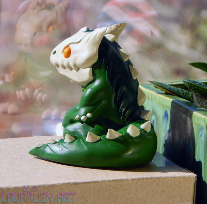 A small, handpainted figurine of SCP-682: a cute lizard monster.